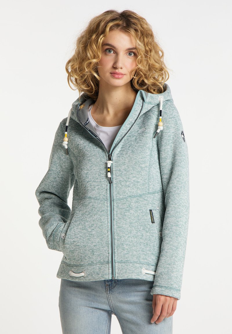 Ljus teal zip-jacka med texturerad tyg, dragsko i huvan och fickor. Har kontrastsömmar och en logotyp på ärmen.