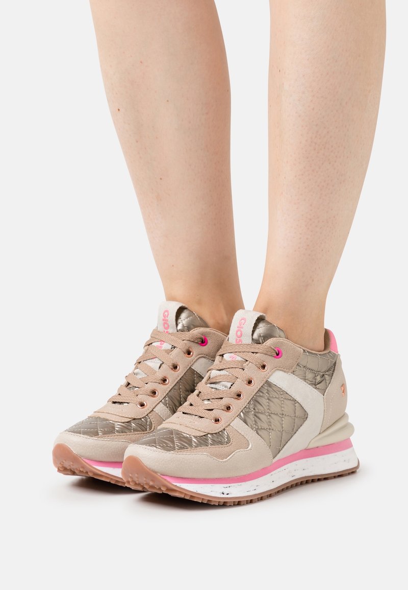 Sneakers beige con dettagli metallici trapuntati, particolari rosa e suola in gomma texturizzata. Presentano design con lacci e pannelli a contrasto.