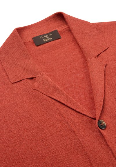 Cardigan en maille couleur rouille avec un col plié, un bouton unique foncé, et une étiquette noire portant l'inscription "SLOWEAR ZANONE icelino".