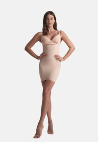Abito aderente color nude con spalline regolabili, presenta un design con apertura sul petto, realizzato in tessuto liscio ed elasticizzato.