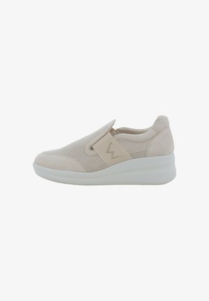 Sneaker beige slip-on con tomaia traforata, collo imbottito, suola piatta e cinturino decorativo con piccoli borchietti sul lato.