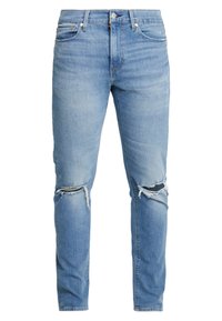Jeans de denim ajustados de color azul claro con desgastes y rotos en ambas rodillas y estilo clásico de cinco bolsillos.