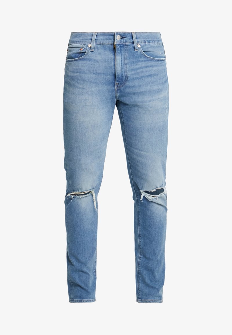 Jeans de denim ajustados de color azul claro con desgastes y rotos en ambas rodillas y estilo clásico de cinco bolsillos.
