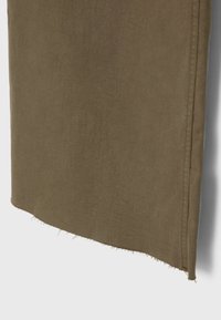 Tissu vert olive avec une finition texturée, présentant un ourlet brut et des détails de couture latérale. Design simple, sans motifs ni éléments métalliques.