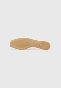 Beige sko sula med en slät yta, gummistruktur och horisontella spår för grepp. Odekorerad design, subtilt böjd form.