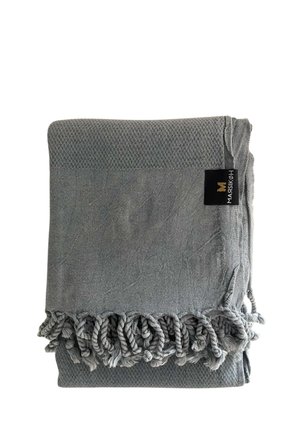 Gråt vævet tekstil foldet med snoede frynser på den ene kant og en sort label syet nær kanten.