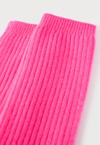 Ριμπ ζεστά καλύμματα ποδιών σε ροζ χρώμα από απαλό υλικό, με κάθετες ρίγες και πλεκτή υφή, που ενισχύουν τη ζεστασιά και την ευελιξία.