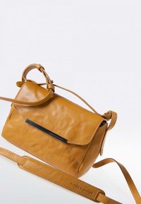 Schultertasche aus senfgelbem Leder mit einem Klappenverschluss, genähten Details und einem verstellbaren Riemen. Verfügt über ein schwarzes Metall-Logo.