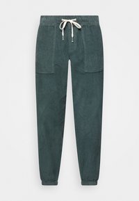 Manšestrové tepláky v mírně tlumené tyrkysové barvě, s elastickým pasem na stažení šňůrkou, dvěma předními kapsami a zužovanými manžetami.