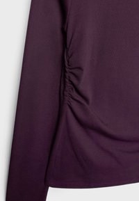 Maglietta a maniche lunghe in tessuto viola scuro, con dettagli arricciati sui lati e texture liscia, dalla silhouette aderente e orlo pulito.