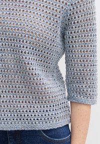 Häkeloberteil mit einem blauen und silbernen gewebten Muster, lockerer Passform, Dreiviertelärmeln und einem strukturierten, offenen Design.