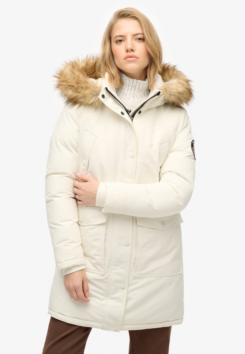 Hvid isoleret parka med en pelsforet hætte, der har lynlås- og trykknaplukning, to forlommer og en glat, glansfuld stoffinish.