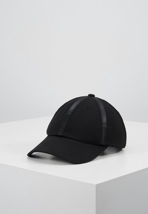 Black baseball cap with glossy black stripes along the panels, resting on a white surface against a plain gray background.