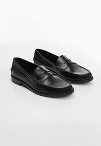 Svarta läderskor i loafermodell med sydda detaljer, platt sula och något rundad tå. Slät textur med en minimalistisk design.