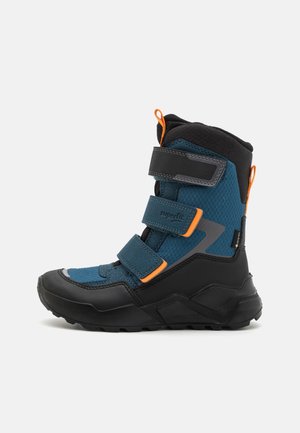 Kindermittelstiefel für den Winter aus blauem und schwarzem Stoff, mit drei Klettverschlüssen, orangen Zuglaschen und einer robusten Sohle, Seitenansicht.