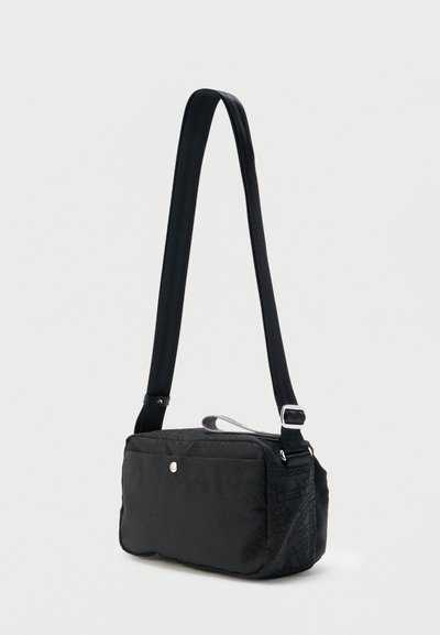 Μαύρη ορθογώνια τσάντα ώμου με ρυθμιζόμενο λουρί, μπροστινή τσέπη και διακριτική ασημί λεπτομέρεια κουμπιού σε ουδέτερο φόντο.