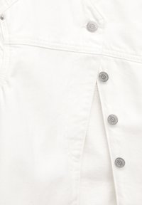 Witte denimjas met zilveren drukknoopjes, gestructureerde naden en textiel. Het ontwerp heeft een lichte open flap aan de voorkant.