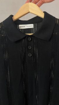 Čierna polo košeľa značky Bershka so štruktúrovaným pleteným vzorom, obsahujúca tri gombíky a klasický dizajn goliera. Materiál vyzerá ľahký.