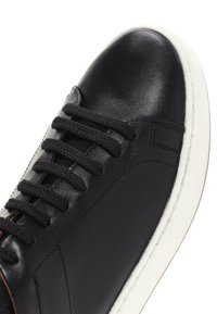 Czarne skórzane sneakersy z okrąłym noskiem, kontrastującą białą gumową podeszwą i czarnymi płaskimi sznurówkami. Charakteryzują się gładką fakturą i minimalistycznym designem.
