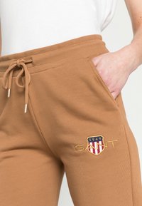 Bruna sweatpants har en dragsko i midjan, sidofickor och en broderad logotyp med en skölddesign och året 1949.