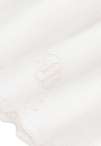 Λευκό υφασμάτινο ύφασμα με λεπτή ανάγλυφη υφή, με εξαιρετικά μπεζ κεντητό μονόγραμμα και ευαίσθητες κυματιστές άκρες.