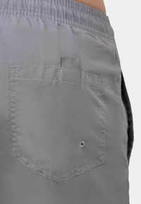 Shorts gris en tissu léger avec une taille élastique, une poche arrière plaquée et des détails de couture pour plus de durabilité.