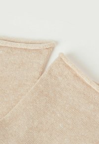 Beige Baumwollstoffstücke mit einer feinen gerippten Textur und einem weichen, gerollten Saum, zwei überlappend in einer Nahaufnahme.