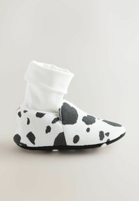 Calzado tipo calcetín blanco con estampado de vaca negro. Parte superior de tela suave, puntera redondeada y suela texturizada para un buen agarre. Diseño minimalista sin adornos.
