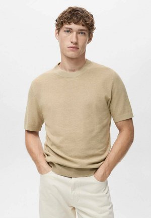Beige kortærmet strikket sweater med rund hals, der har en tekstureret overflade og ribbet kant. Bæres med lyse bukser.