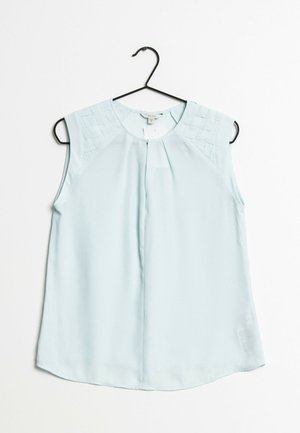 Blouse sans manches bleu clair avec détail tissé sur les épaules, encolure ronde et pli central, suspendue à un cintre noir sur un fond blanc.