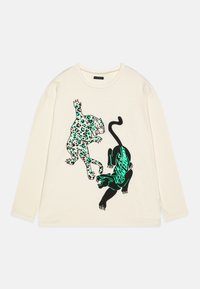 Kreemipolor ei pika varrukaga T-särk, millel on värvikas leopard ja must panter, koos rohelise tekstiga. Valmistatud pehmest puuvillast materjalist.