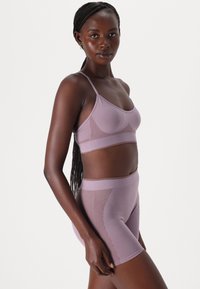 Lilla sømløs bralette og høyt liv shorts-sett med ribbede sidepaneler. Mykt, elastisk stoff. Jevn tekstur med tynne stropper.