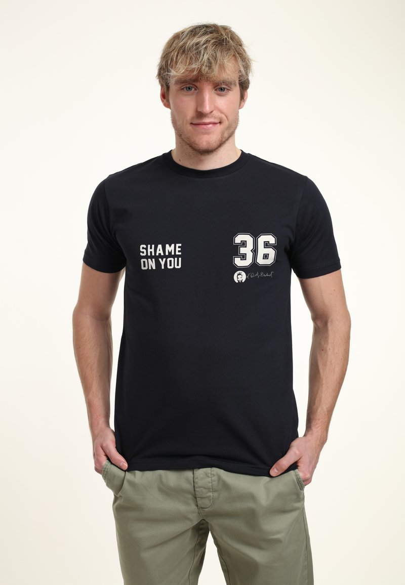 Černé bavlněné tričko s bílým textem "SHAME ON YOU" a číslem "36" na přední straně. Krátké rukávy, design s kulatým výstřihem.
