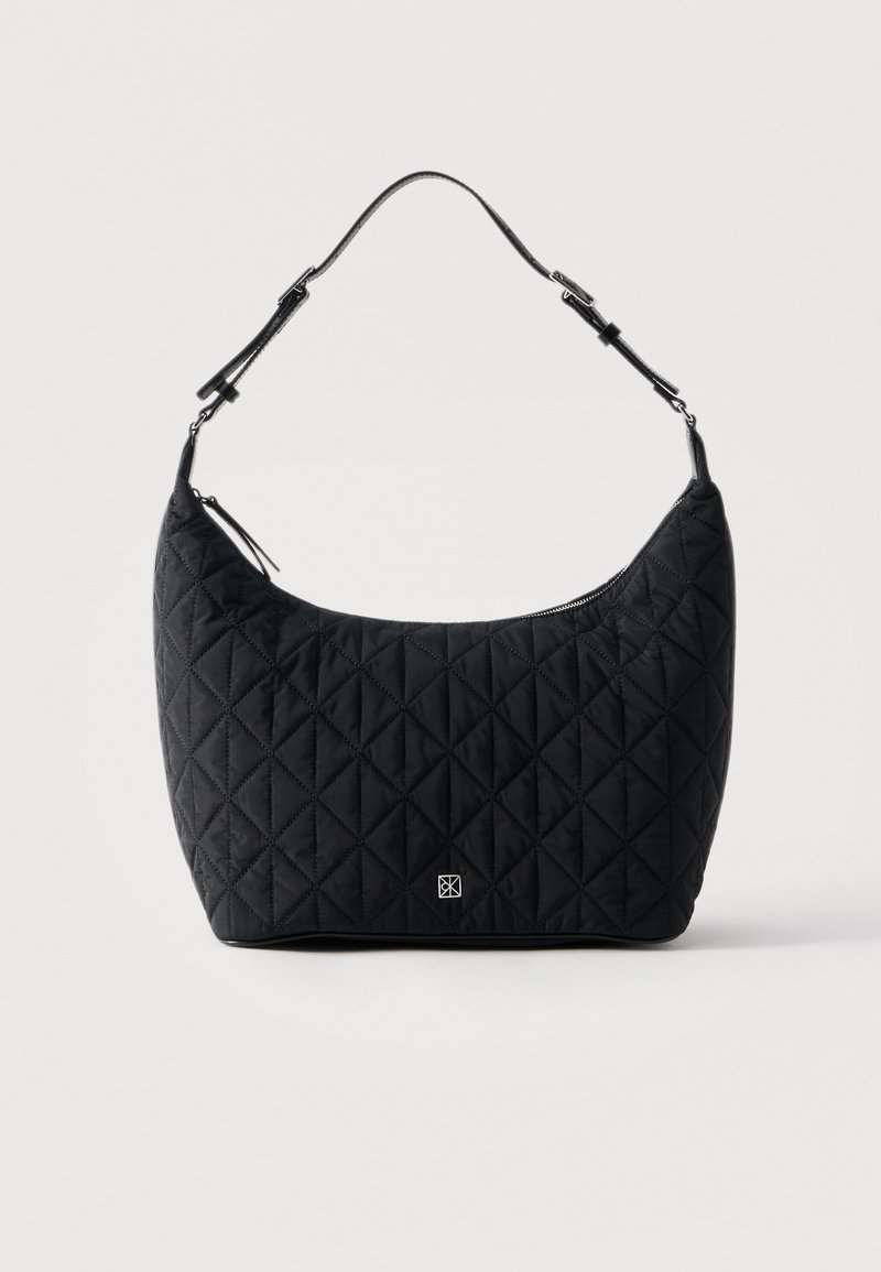 Μαύρη καπιτονέ τσάντα ώμου με ρυθμιζόμενο λουρί, καμπυλωτό φερμουάρ στην κορυφή και μικρό ασημένιο λογότυπο στο κέντρο μπροστά.