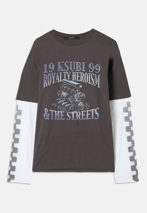 Mørk grå t-skjorte med lange hvite ermer, med grafisk trykk av en motor og tekst i blått. Rutete mønster langs ermene.