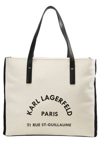 Torba na zakupy z płótna z czarnymi skórzanymi uchwytami; w kolorze kremowym z odważnym czarnym napisem "KARL LAGERFELD PARIS" oraz adresem.