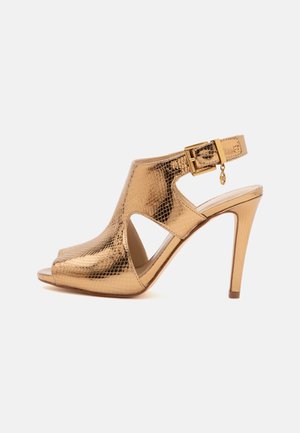Sandale dorée à talons hauts avec surface texturée, bout ouvert, côtés découpés et bride de cheville réglable avec petite boucle décorative.