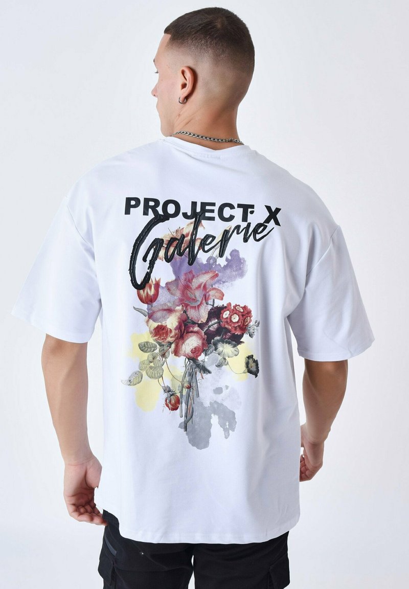Witte katoenen t-shirt met een grote bloemenprint op de achterkant, met "PROJECT X" en "Galerie" in vette zwarte letters boven het ontwerp.