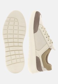 Baskets décontractées beige et taupe avec semelle texturée, fermeture à lacets et col rembourré, vues de la semelle et de côté.