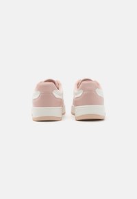 Adidași sintetici roz cu accente albe, ample la spate și din material texturat. Talpă din cauciuc cu o ușoară diferență de nuanță. Design minimalist.