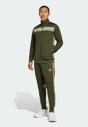 Green sports tracksuit made of smooth fabric, featuring a zip-up jacket with a light green panel and orange logo, and matching tapered pants with stripes.