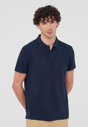Polo in navy realizzato in un mix di cotone, con colletto classico, maniche corte e patta con due bottoni. Texture liscia, forma aderente.