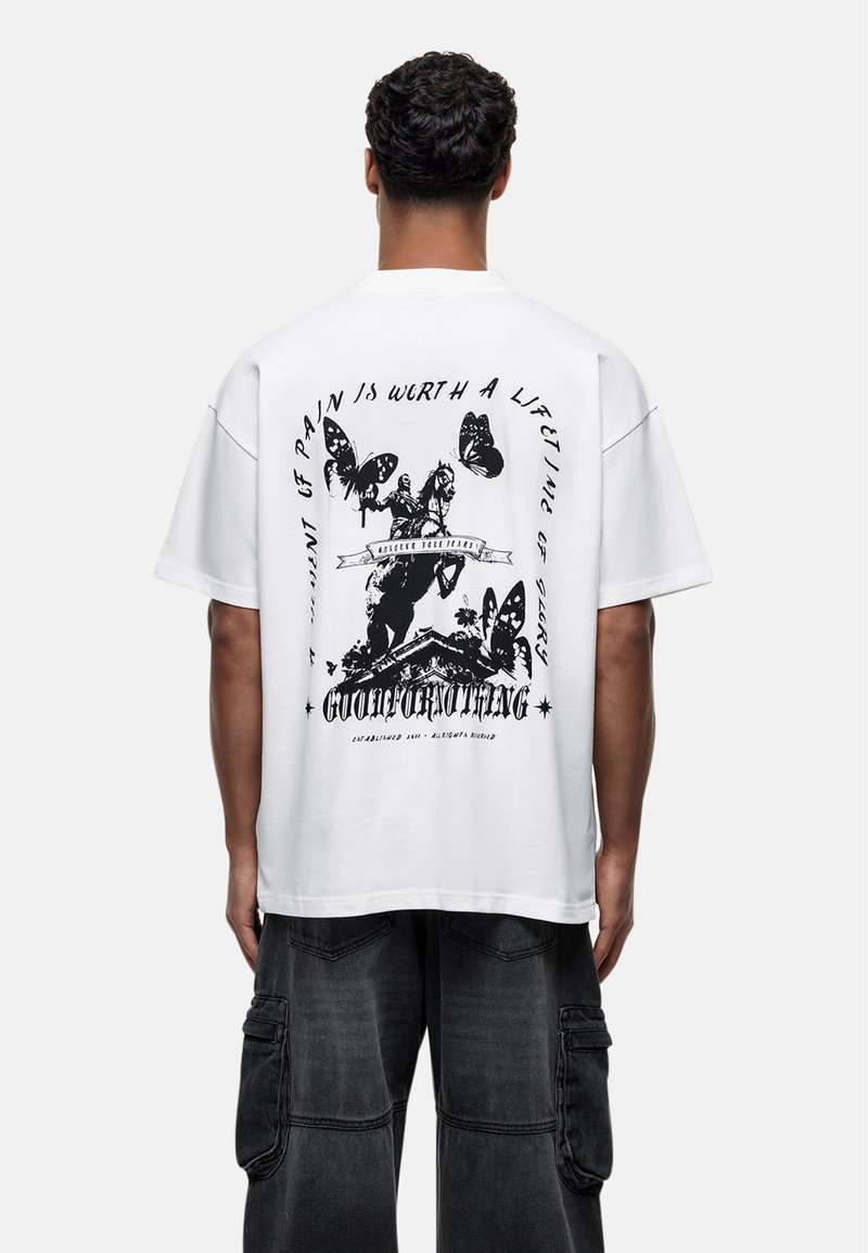 Biała, oversize'owa koszulka z grafiką, z czarnym nadrukiem przedstawiającym motyle i postacie, okrągły dekolt i krótkie rękawy. Design na plecach zawiera tekst.