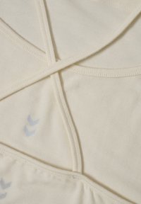 Cream-colored fabric with crisscross straps and a soft texture. Light blue accents featuring a chevron pattern near the lower edge.