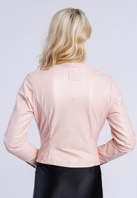 Lichtroze leren jasje met een aansluitend ontwerp, voorzien van een klein logopatch op de achterkant. Gladde textuur en getailleerde vorm.