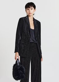 Schwarzer Samtanzug mit einem strukturierten, gemusterten Design. Verfügt über einen taillierten Blazer und weit geschnittene Hosen. Akzentuiert mit einer flauschigen schwarzen Handtasche.