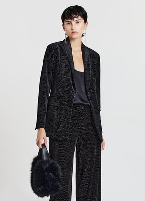 Schwarzer Samtanzug mit einem strukturierten, gemusterten Design. Verfügt über einen taillierten Blazer und weit geschnittene Hosen. Akzentuiert mit einer flauschigen schwarzen Handtasche.