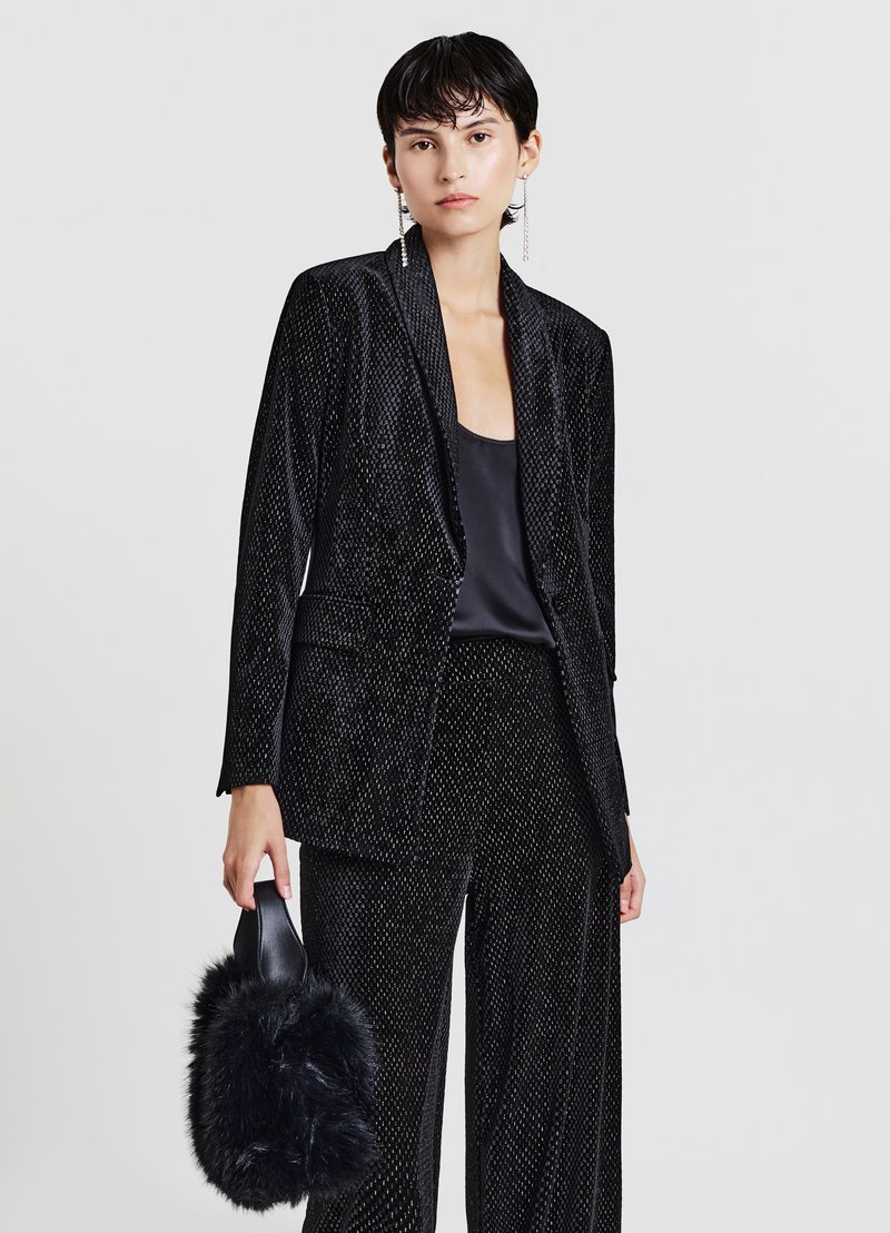 Schwarzer Samtanzug mit einem strukturierten, gemusterten Design. Verfügt über einen taillierten Blazer und weit geschnittene Hosen. Akzentuiert mit einer flauschigen schwarzen Handtasche.