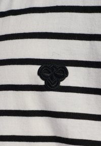 Hvid- og sortstribet stof med et tekstureret sort broderet logo. Skjorten har vandrette striber og en blød tekstur.