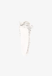 Producto cosmético en polvo blanco con una textura de aplicación suave, mostrando partículas finas y una franja delgada y cremosa sobre un fondo claro.